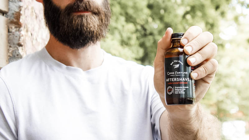 Bearded man holding natural aftershave